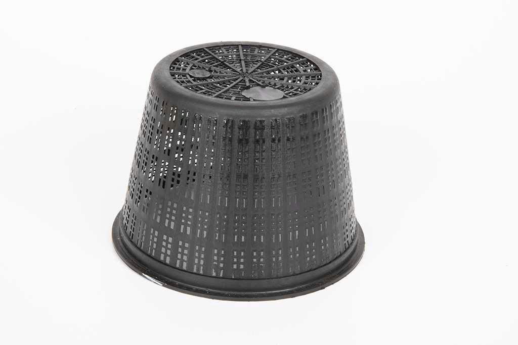 Black perforated plastic plant pot turned upside down on white background